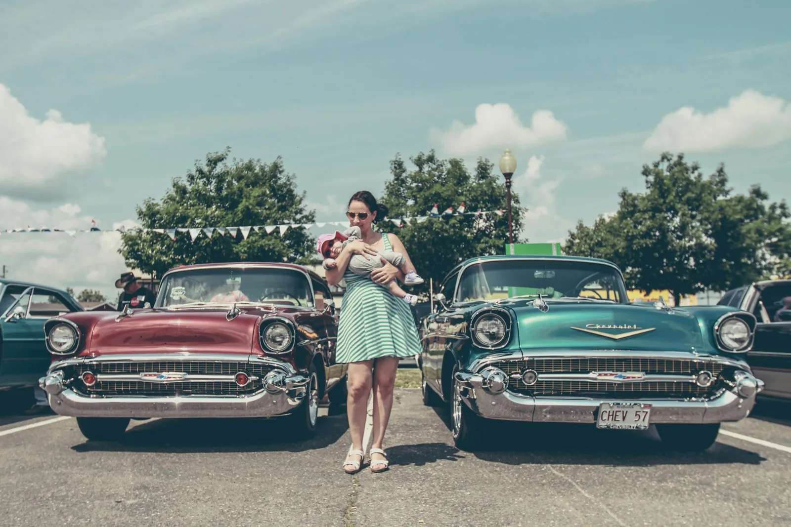 A mother and child between two 1957 Chevrolets